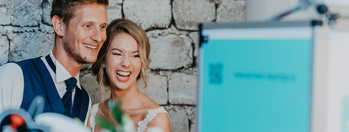 lachendes Brautpaar bei ihrer Fotobox Party auf der Hochzeit